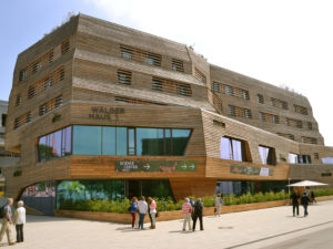 Die Fassade aus Holz und Glas von dem futuristischen Wälderhaus mit spazierenden Personen davor