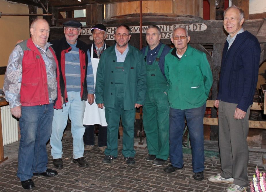 Mehrere Personen in Arbeitsbekleidung stehen in der Mühle