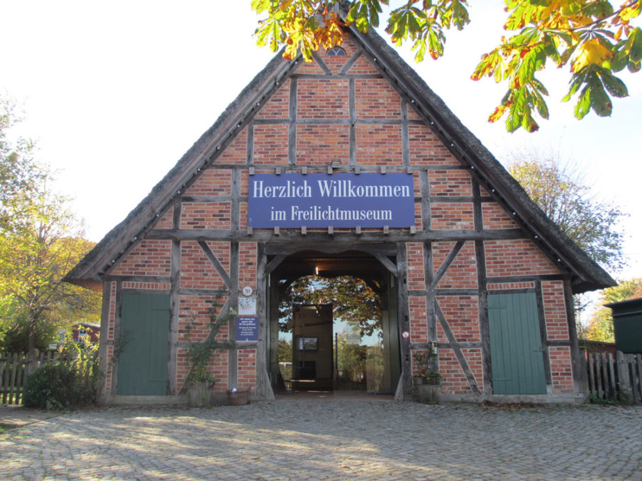 Fachwerkhaus aus roten Backsteinen mit geöffnetem großen Dielentor als Eingangsbereich