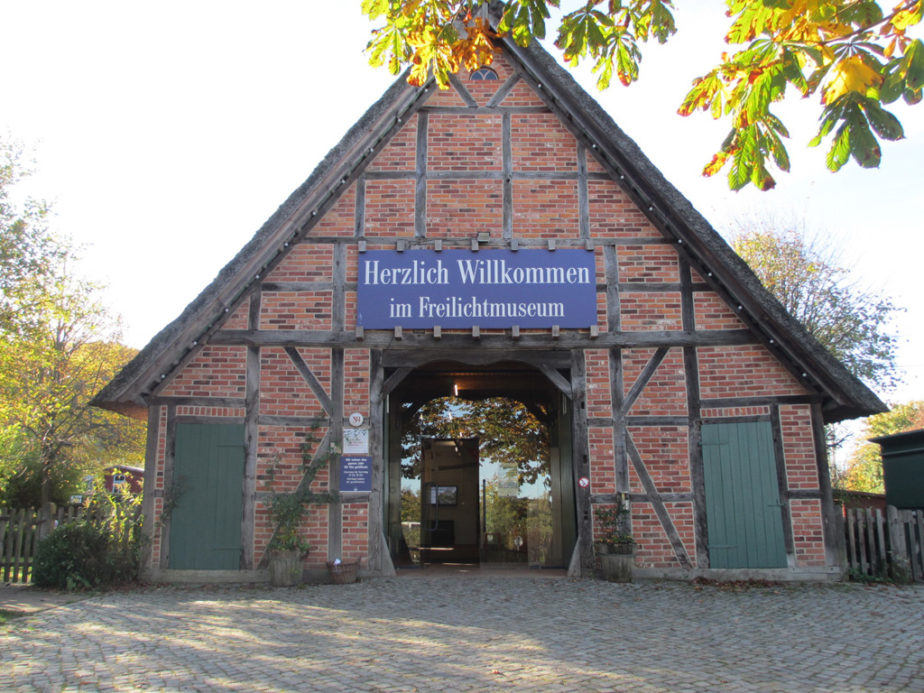 Fachwerkhaus aus roten Backsteinen mit geöffnetem großen Dielentor als Eingangsbereich