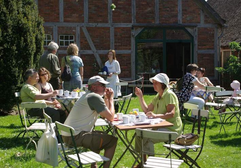 Tische und Stühle im Garten vor einem Fachwerkgebäude