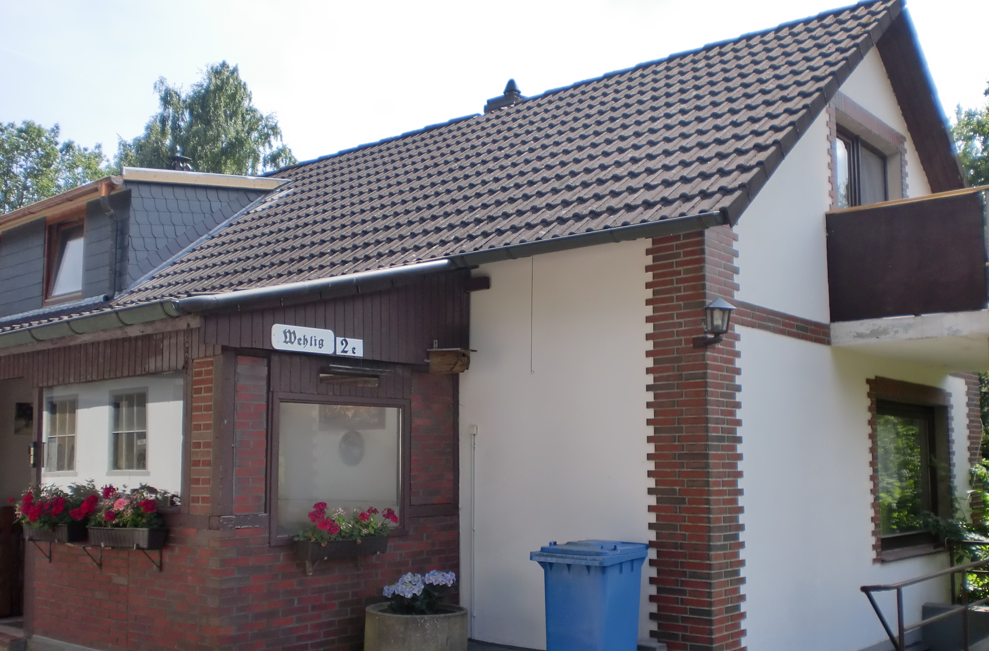 Aussenansicht Einfamilienhaus mit kleinem Anbau und Blumenkästen an Fenstern